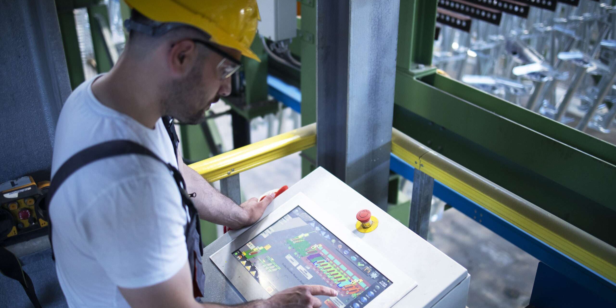 Factory worker monitoring industrial machines and production remotely in control room. manutenzione predittiva