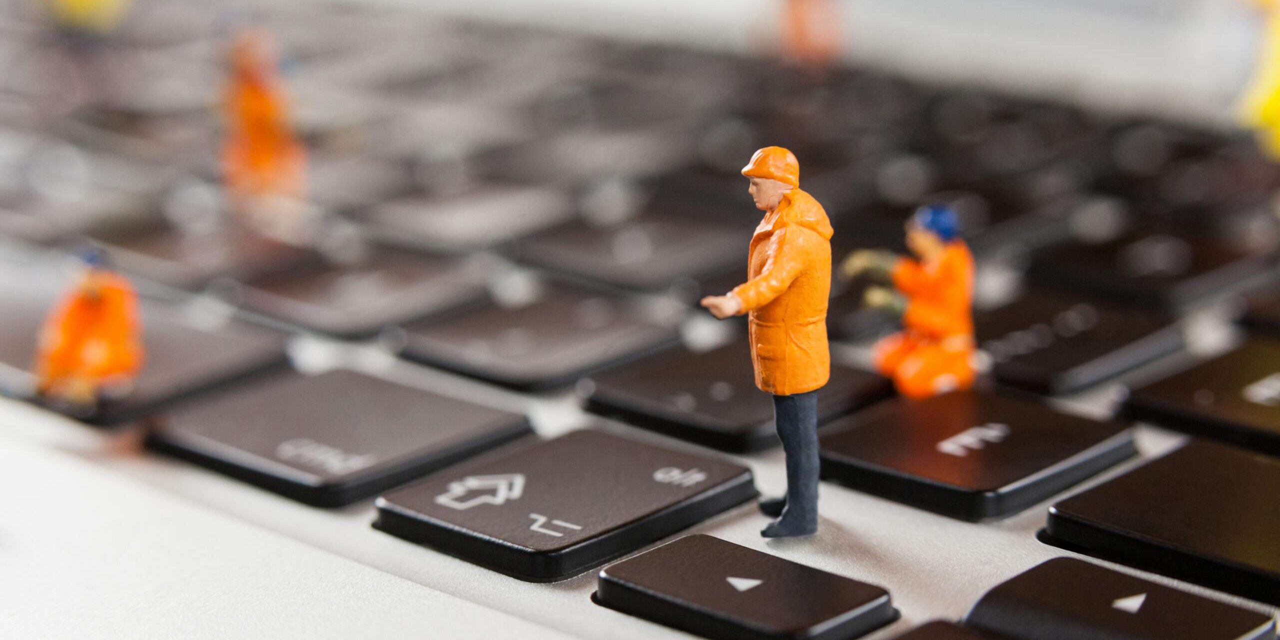 Miniature workmen repairing a laptop keyboard Software d.lgs 81/08